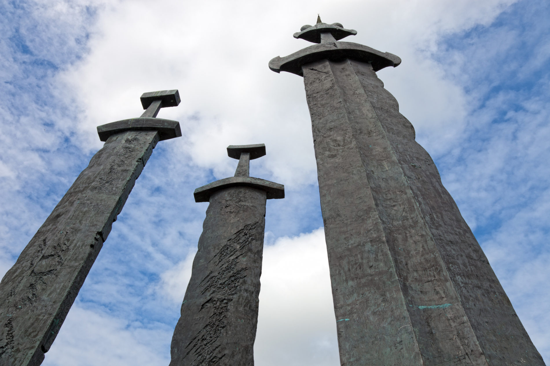 Three large stone swords against the blue sky.